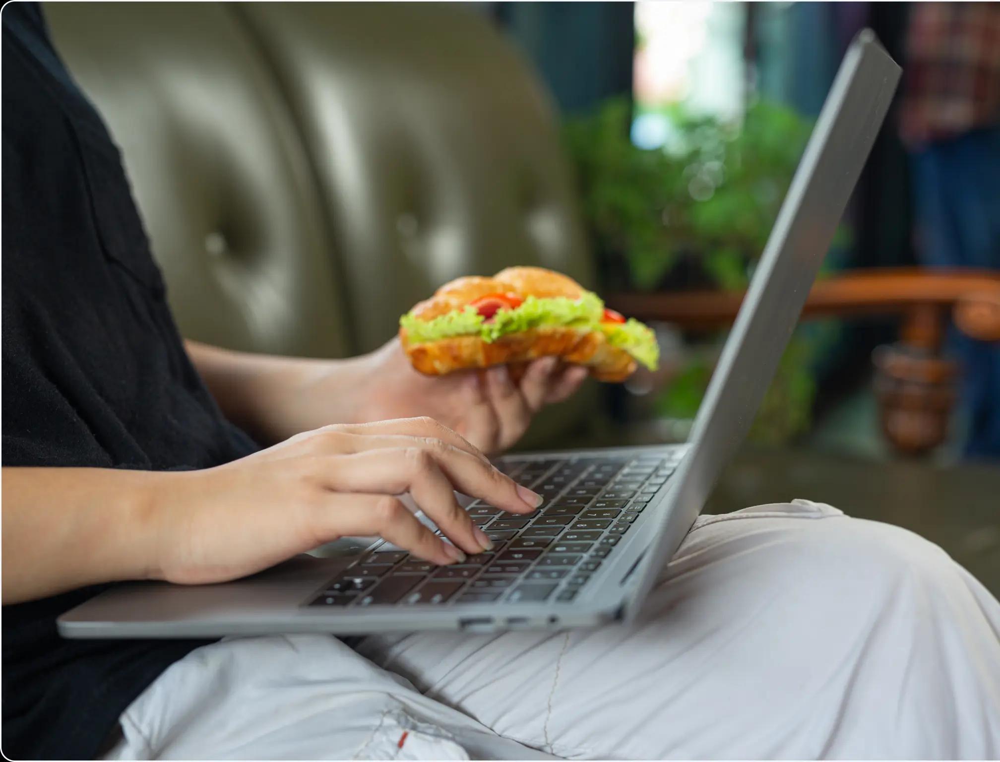 a man eating food and using a computer