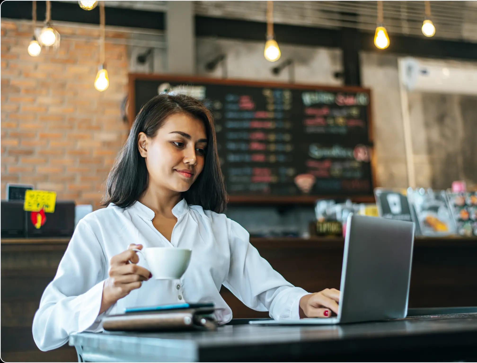 a woman using a computer and drinking coffee