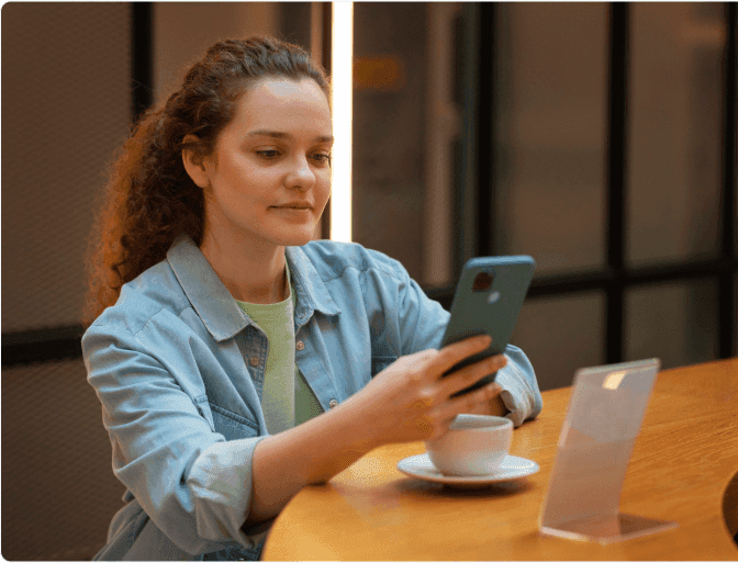 woman with a cup of coffee and holding a phone